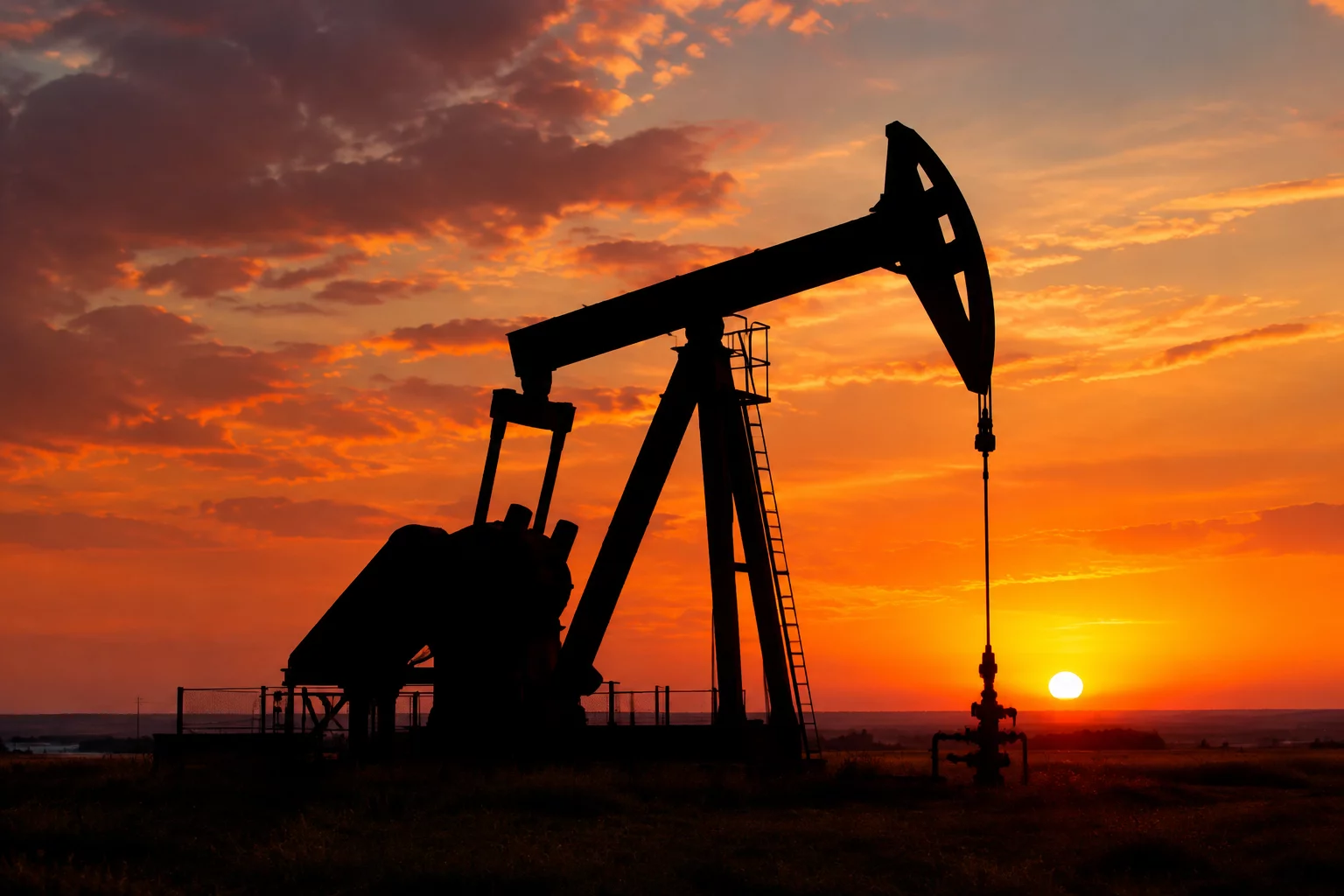 An oil pump jack silhouetted against a setting sun, representing the energy sector.